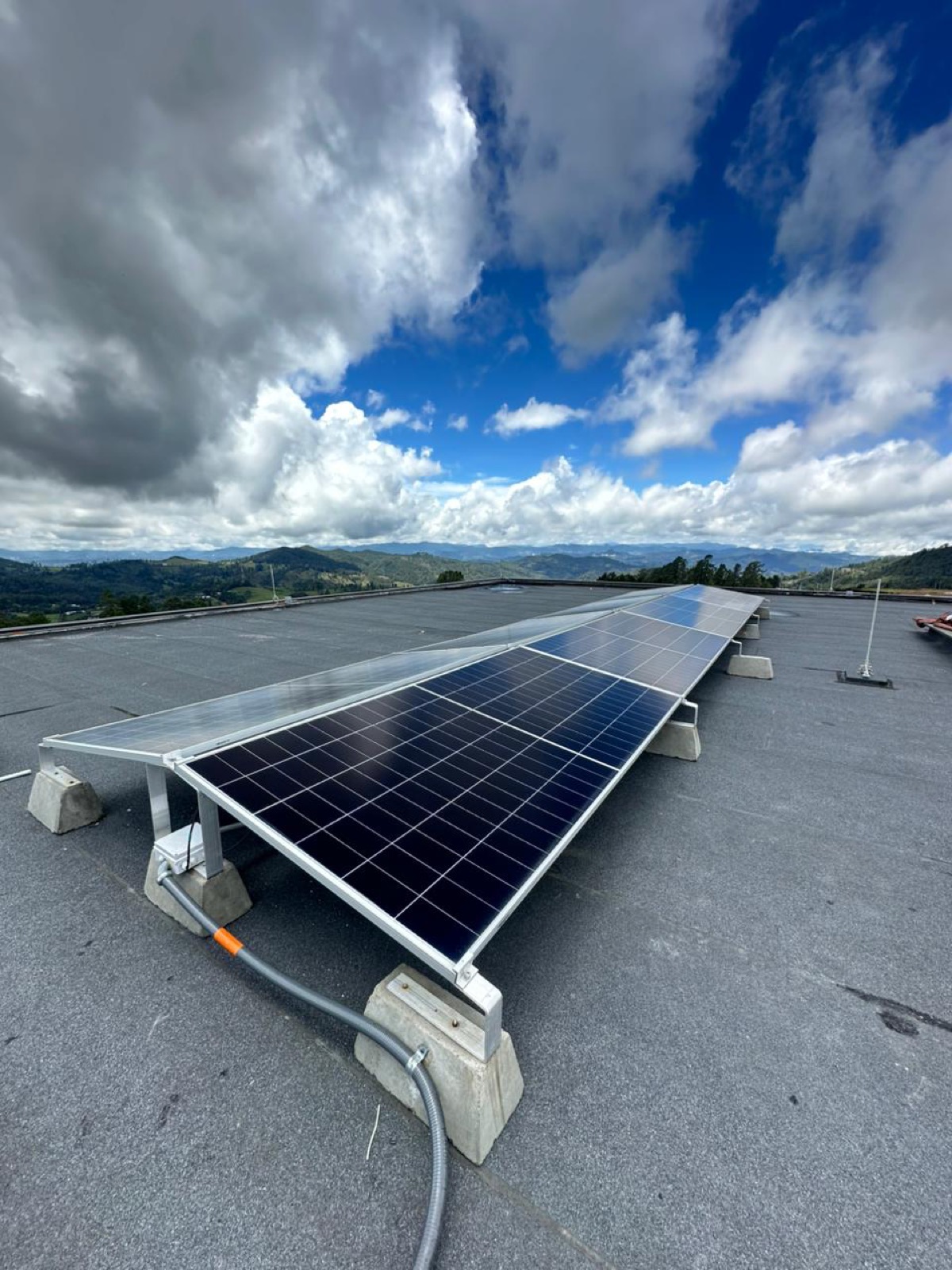 Paneles solares fotovoltaicos instalados en cubierta, con cordillera de Antioquia al fondo — proyecto de energía solar de Octava Ingeniería